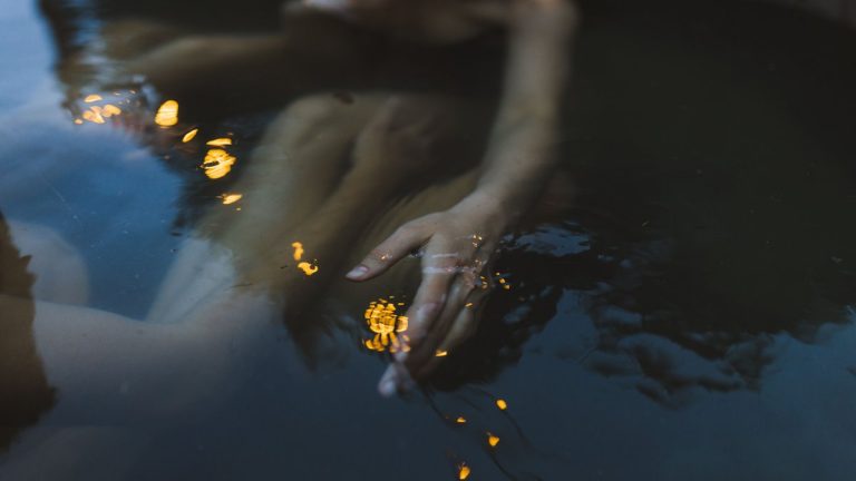 Blurred reflection of a person in water with serene evening lighting capturing a tranquil mood