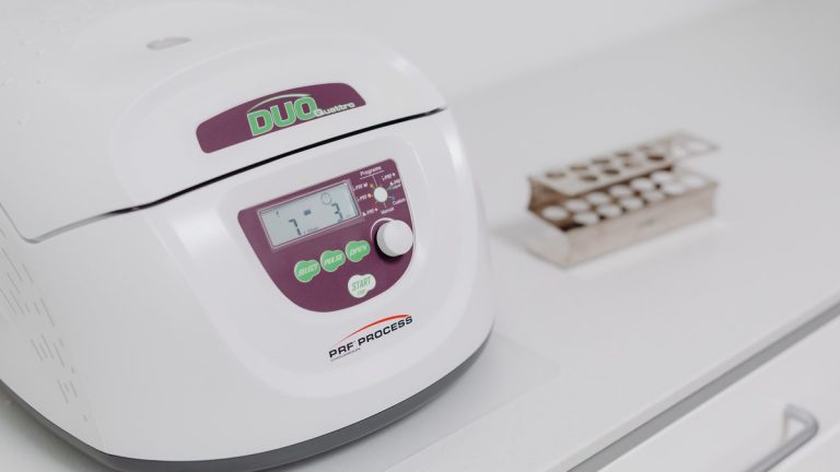 Close-up of a modern laboratory centrifuge on a sterile white surface, used in medical testing