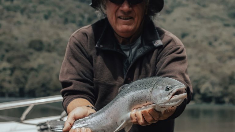 An angler holding a freshly caught trout beside a northern lake