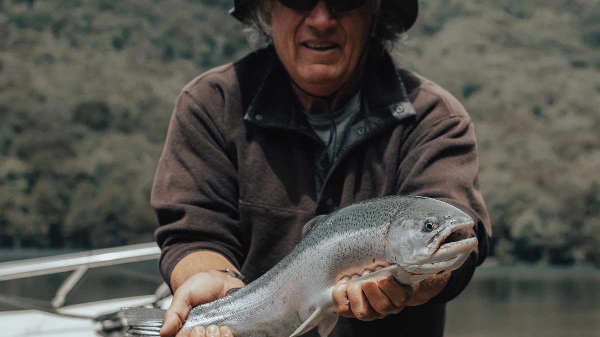 An angler holding a freshly caught trout beside a northern lake