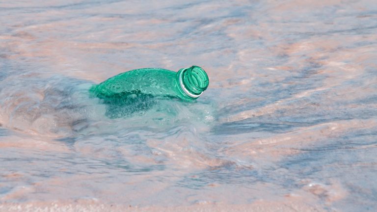 Close-up of a plastic bottle polluting the ocean shore, highlighting environmental issues
