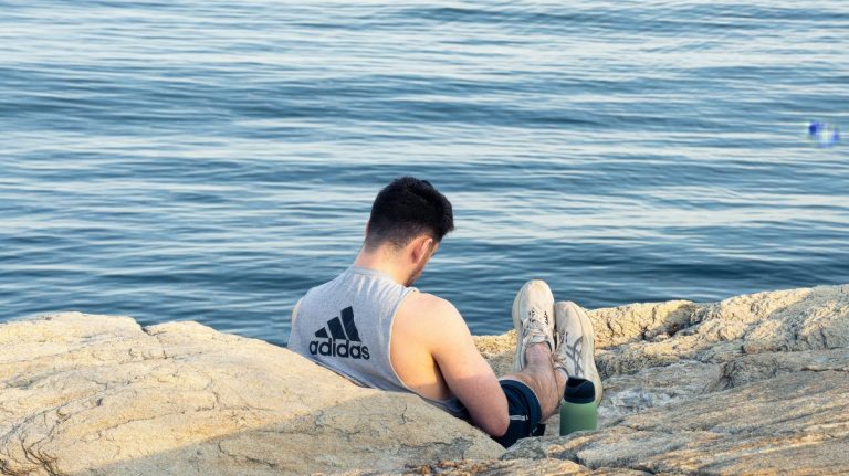 A person sitting quietly on a rocky coast beside the sea