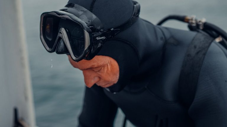 A scuba diver wearing a mask and preparing to enter the water