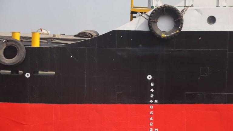 Detail of a ship's hull with hydrodynamic markings and tire fender