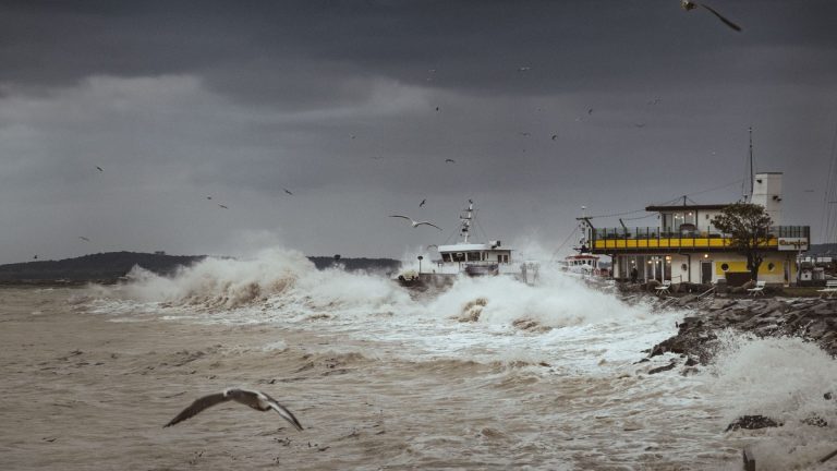 Dramatic storm over the Baltic Sea with crashing waves and seagulls near a pier in RĂ¼gen, Germany