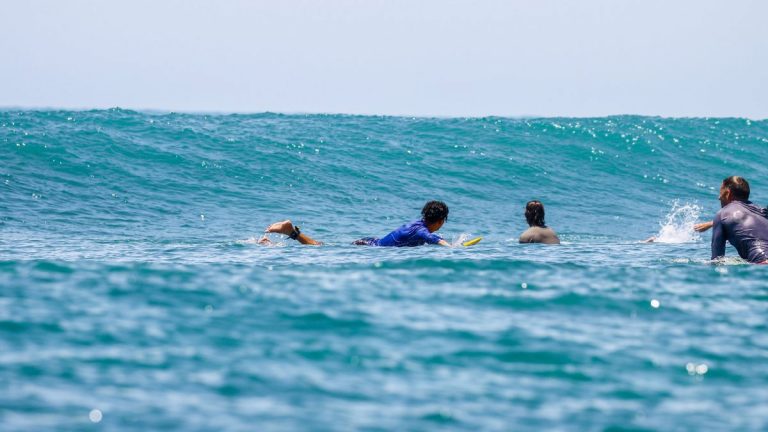 Four surfers paddling together in the ocean
