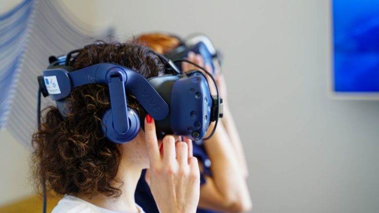 Two women using VR headsets, fully immersed in virtual reality technology indoors
