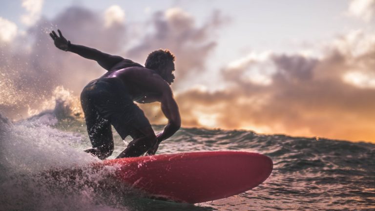 A surfer riding an ocean wave at sunset