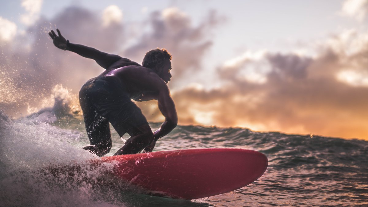 A surfer riding an ocean wave at sunset