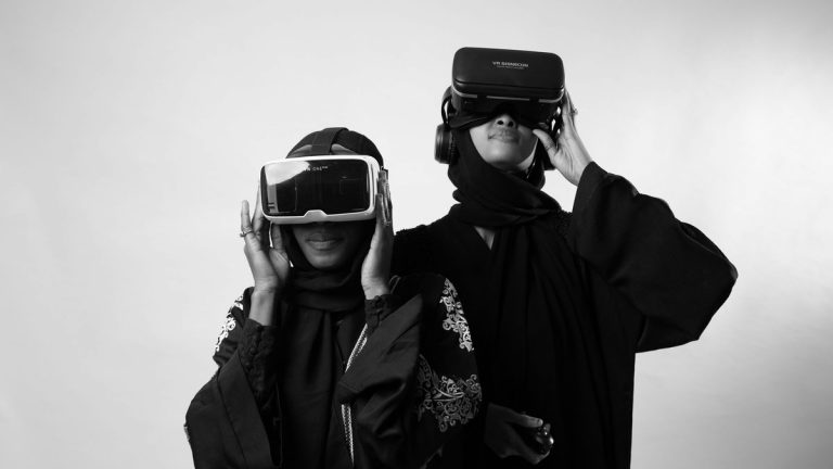 Two women in traditional attire enjoying virtual reality, showcasing modern technology