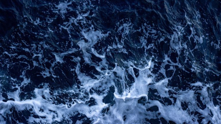 Aerial view of crashing ocean waves captured in Çanakkale, Türkiye, showcasing white foam and dark blue water