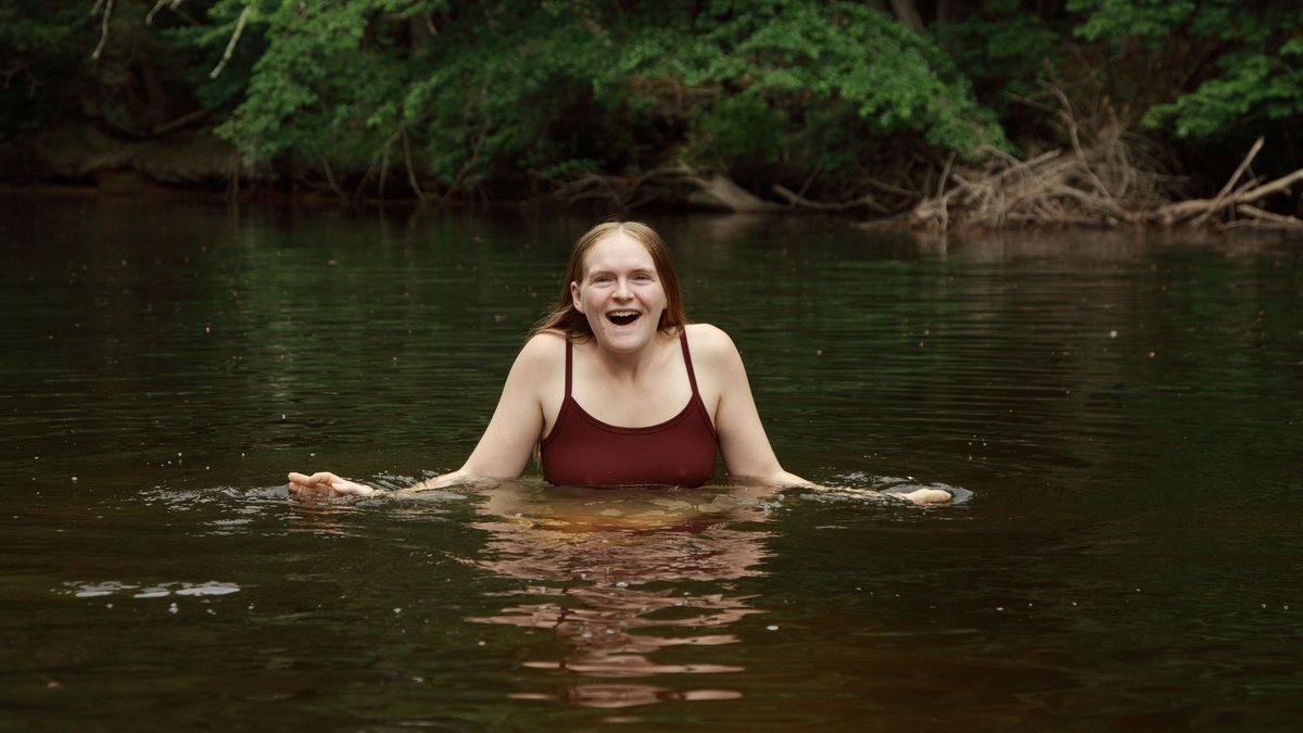 A woman swimming in a quiet lake surrounded by green vegetation