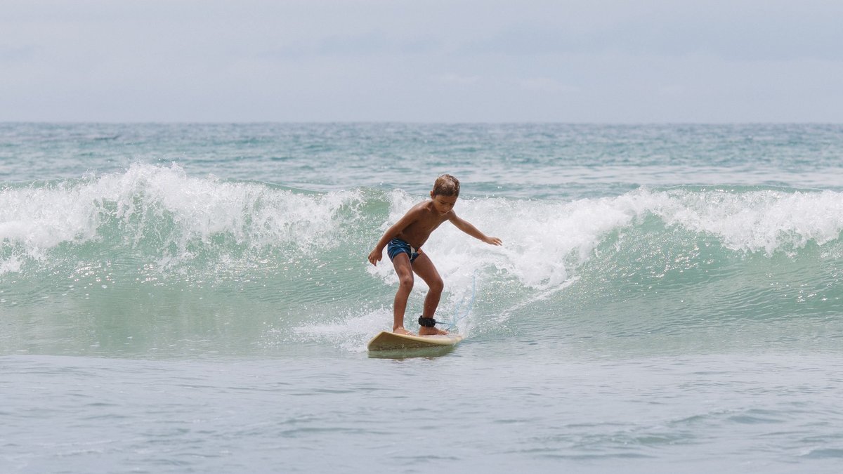 A young surfer riding a gentle ocean wave