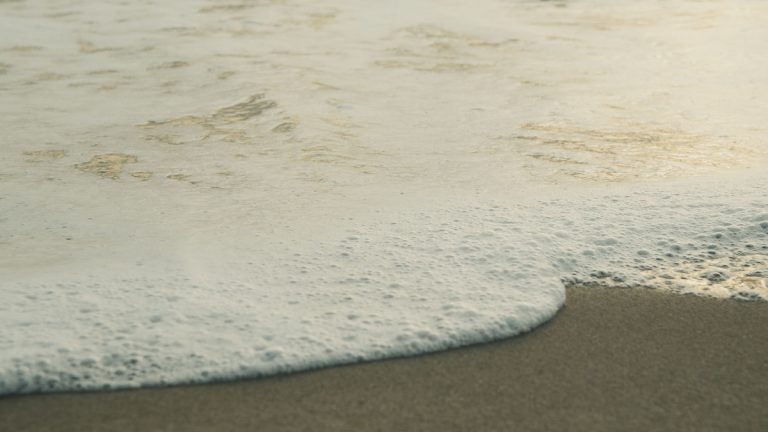 Sea foam washing across a sandy beach