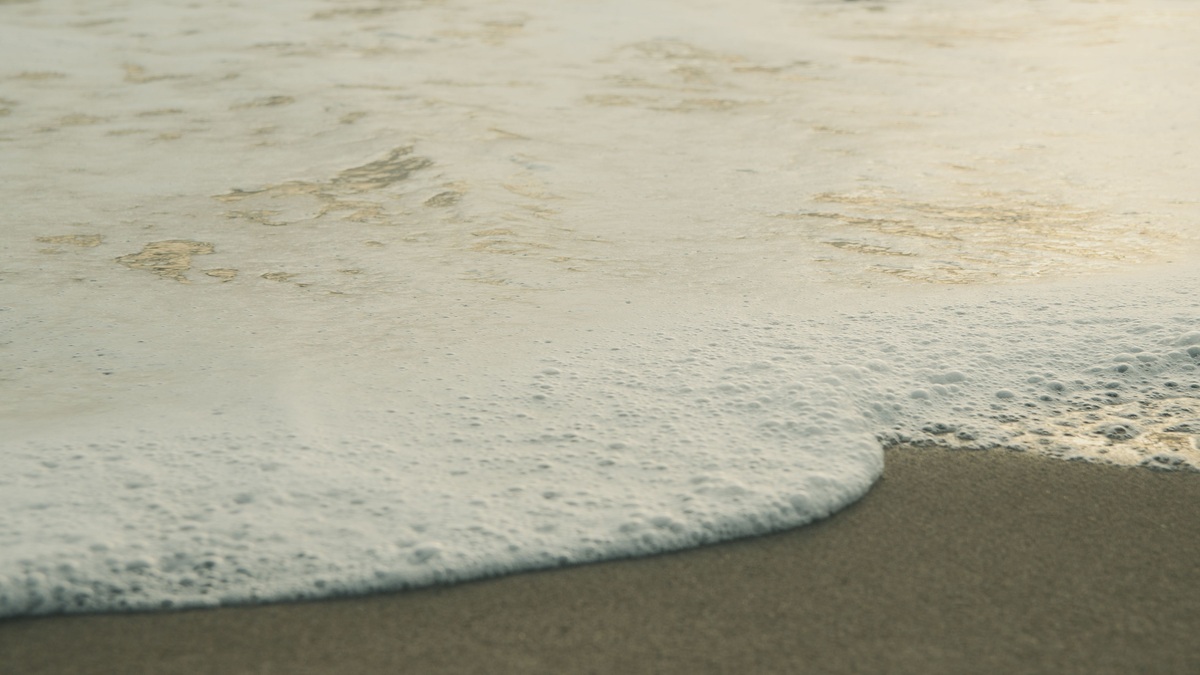 Sea foam washing across a sandy beach