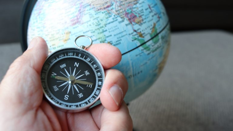 A compass held in front of a globe