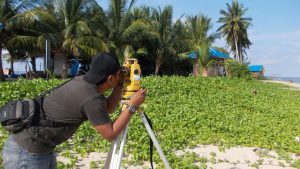 A surveyor measuring elevation beside the coast