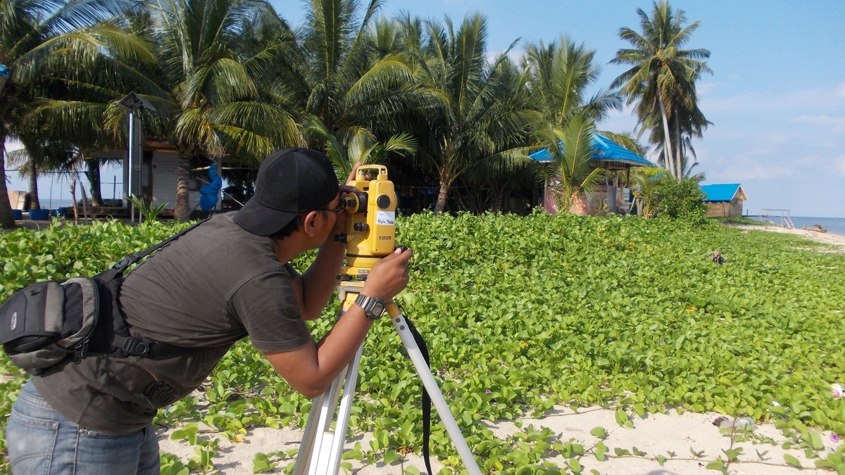 A surveyor measuring elevation beside the coast